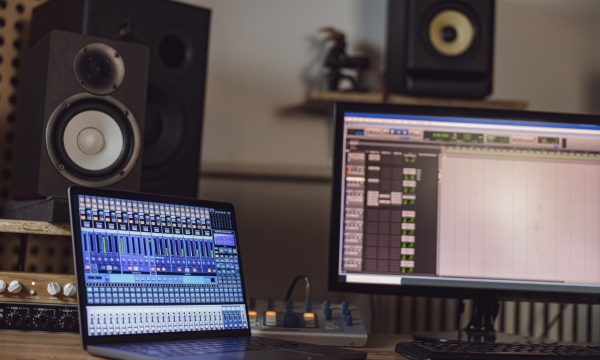 Close-up of switched on laptop and monitor screen on table in the sound engineer room in a broadcasting and recording studio